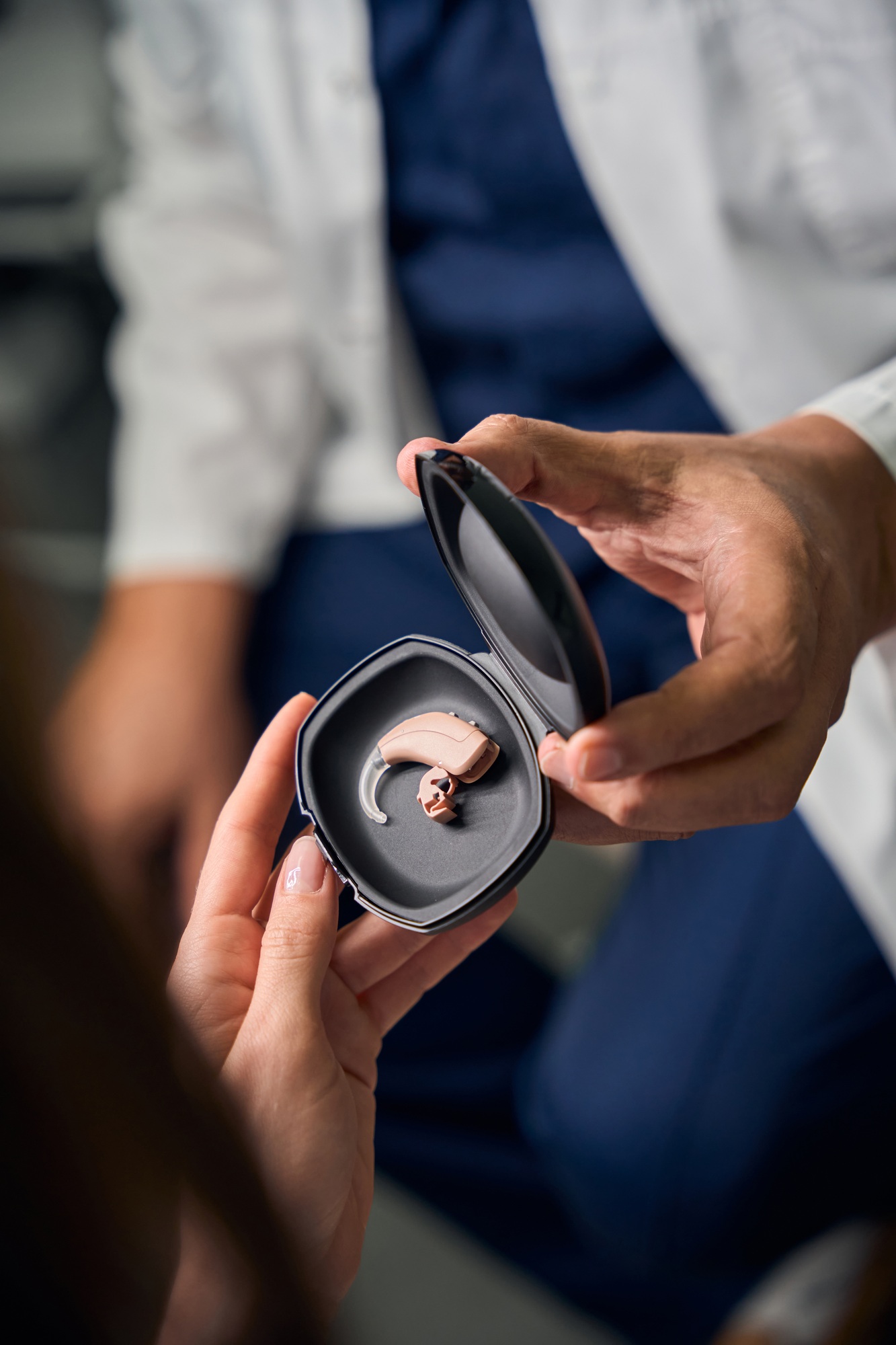 Caucasian doctor holding hearing aid case for patient