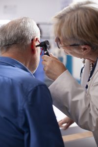 Medico controlla l’orecchio di un paziente anziano durante una visita specialistica